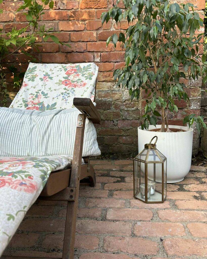 brick pavers with lantern ornament and floral decking chair to the left